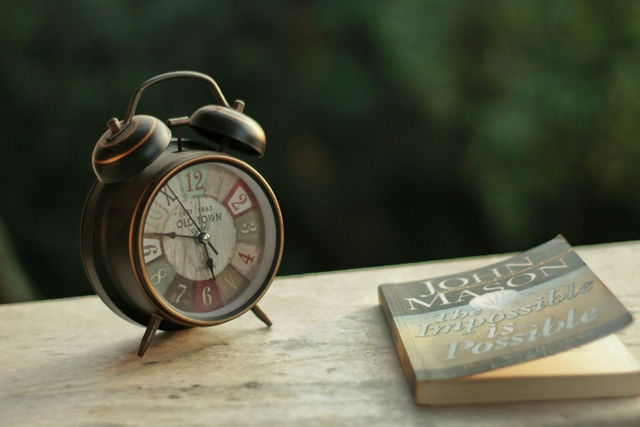 An alarm clock next to a book on a table, representing a fasting eating window