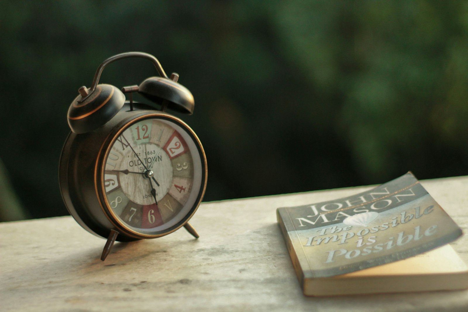 An alarm clock next to a book on a table, representing a fasting eating window
