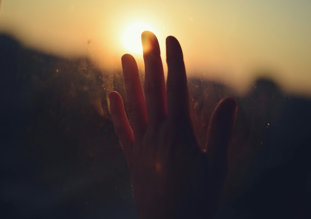 A hand reaching toward a sunset, symbolizing hope in recovery